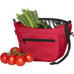 A red lunch bag with a shiny interior, holding green leeks and vegetables, accompanied by a bunch of red tomatoes.