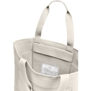 A beige tote bag with two handles and an interior label, featuring a textured design and open top.