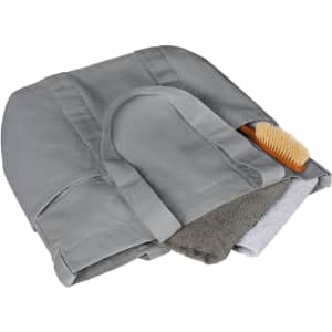 A grey tote bag featuring two towels and a wooden brush inside. The bag has a logo on its surface.