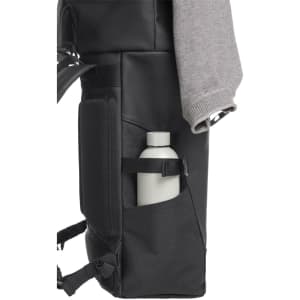 A black backpack featuring a side pocket with a drink bottle and a sweater draped over the top.