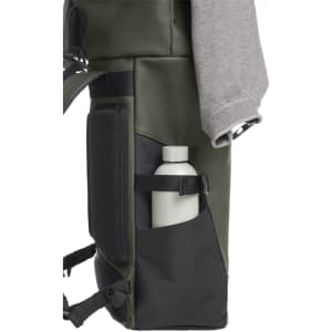 A green laptop backpack featuring a side pocket with a white drink bottle and a gray sweatshirt draped over it.