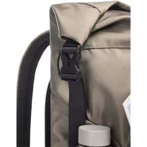 A Mellow Backpack in a muted beige shade with a buckle and a drink bottle visible at the bottom. Features a logo.