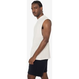 A sleeveless tee in off-white, featuring a simple design and a logo, paired with dark shorts.