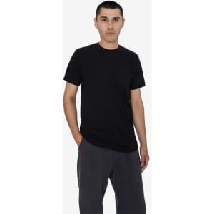A black short sleeve fine jersey crew tee, worn by a model with hands in pockets, against a plain background.