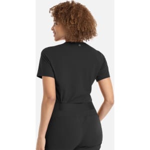 A woman with curly hair wearing a black banded V-neck top, viewed from the back. The top features a logo.