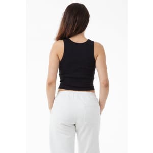 A woman is wearing a black 2x1 rib crop tank top, viewed from the back, paired with white pants.