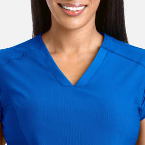 A model wears a blue banded V-neck top, showcasing its neckline and smooth fabric. The top features a branding logo.