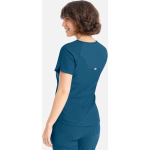 A back view of a blue Embrace Luna Tuckable Y-Neck Top, featuring short sleeves and a logo.