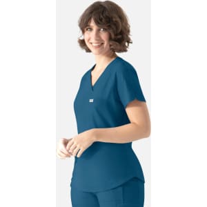 A woman wearing a teal Y-neck top with a pocket, featuring a logo on the chest.