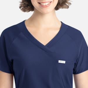 A navy blue Y-neck top featuring a pocket and a small logo on the side. The fabric appears soft and comfortable.