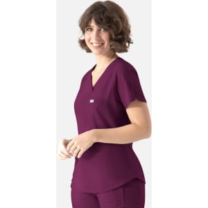 A woman wears a plum-coloured Y-neck top with short sleeves, featuring a small logo on the chest.