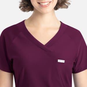 A purple Y-neck top featuring a pocket and a logo, designed for a comfortable fit.