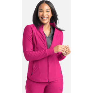 A woman wearing a bright pink full zip track jacket, smiling and standing against a light grey background.
