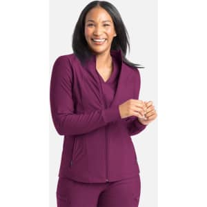 A woman wearing a full zip track jacket in a rich plum colour, smiling and standing against a neutral background.