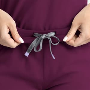 A close-up of a purple mid-rise jogger featuring a tied drawstring at the waistband. The fabric appears soft and comfortable.