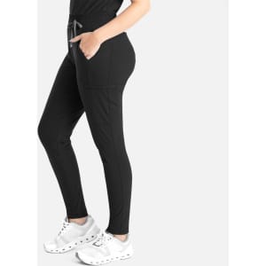 A pair of black tapered leg pants with pockets and a drawstring waist, modelled with white sneakers.