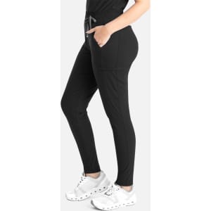 A tapered leg pant in black with pockets and an adjustable drawstring. The model is wearing white sneakers.
