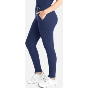 A pair of navy tapered leg pants featuring pockets and an elastic waistband, displayed on a model wearing white shoes.