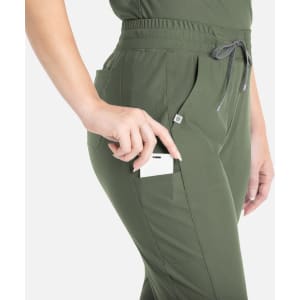 A tapered leg pant in olive green featuring side pockets and a drawstring waist, with a hand placing a card in the pocket.