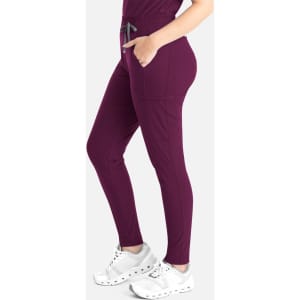 A tapered leg pant in deep burgundy, featuring side pockets and a drawstring waist. The model pairs them with white shoes.