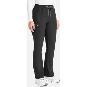 A pair of black bootcut pants with a drawstring waistband and side pockets. The model stands wearing white shoes.