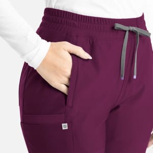A close-up of a woman wearing burgundy bootcut pants with an elastic waistband and a side pocket.