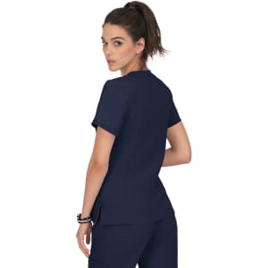 A model wearing a navy blue scrub top with a simple design and a subtle logo on the back.
