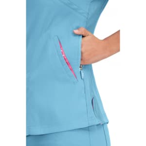 A close-up of a light blue top with pink accents, featuring two zippered pockets on the side.