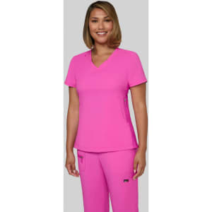 A woman wearing a bright pink top and matching pants, smiling and standing against a grey background. The outfit features a logo.