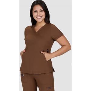 A brown medical top with a relaxed fit, featuring a V-neck and pockets, worn by a smiling model.