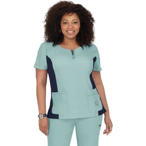A short-sleeved scrub top in teal with navy side panels and two front pockets. Features a logo on the left side.