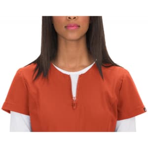 An orange top with a front zip and short sleeves, featuring a round neckline and a logo on the side.