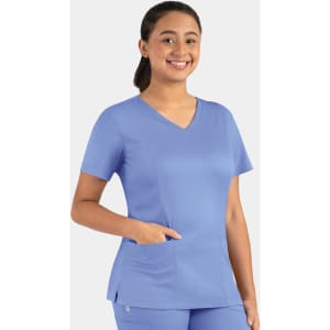 A woman in a light blue double V-neck top with a pocket, smiling against a plain background.