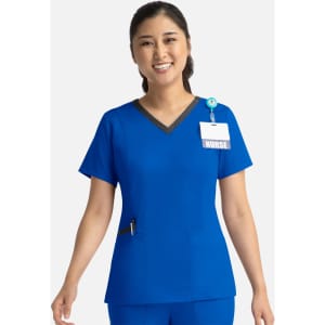 A blue women's top with a contrast V-neck and a pocket, featuring a logo and a name badge holder.