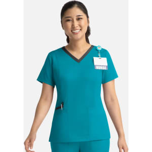 A teal women's top with a contrast double V-neck, featuring a logo and a name badge attachment.