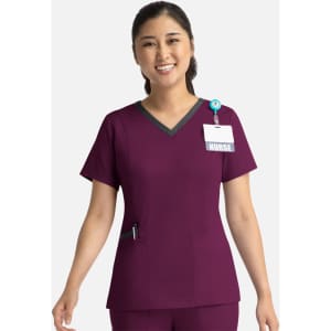 A purple women's scrubs top with a double V-neck design, featuring a patch pocket and a badge holder.