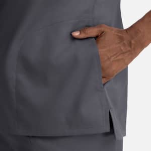 A grey notched crew neck top featuring a side pocket and a relaxed fit. It has a logo on it.
