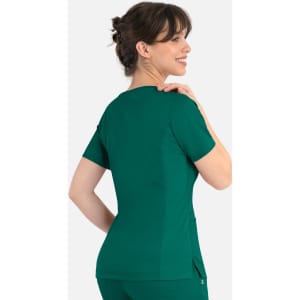 A woman wearing a green curved mock wrap top, showcasing the back design and fit of the garment.
