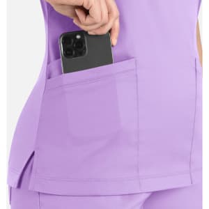 A lilac women's curved mock wrap top featuring side pockets with a smartphone partially tucked inside.