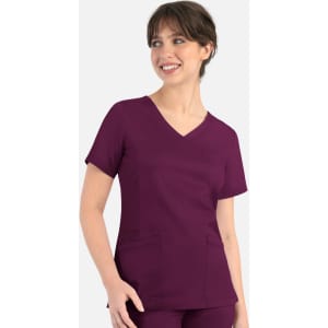 A woman wearing a purple curved mock wrap top with short sleeves and a V-neckline. The top features two pockets.