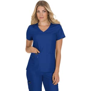 A woman models a blue medical scrub top with a v-neck and pockets, featuring a logo on the sleeve.