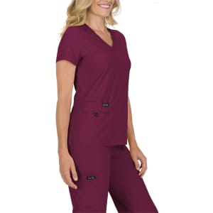 A scrubs top in a deep burgundy colour, featuring a v-neck and short sleeves, worn by a model.