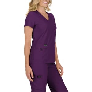 A woman wearing a purple medical scrub top with a v-neck and two front pockets, accompanied by matching pants.