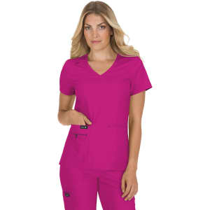 A woman wearing a bright pink scrub top with a V-neck and pockets. The scrub features a logo on the side.