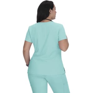 A front view of a woman wearing a short-sleeved, aqua-coloured scrub top. The top features a round neckline and a logo.