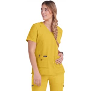 A woman wears a vibrant yellow scrub top with a v-neck and pockets, featuring a logo.