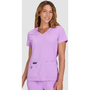 A medical top in light purple, featuring short sleeves and two front pockets, worn by a model.