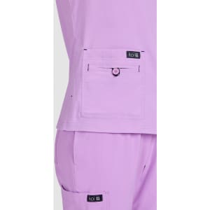 A lilac top featuring a front pocket with a button, alongside matching lilac pants, both with a brand logo.
