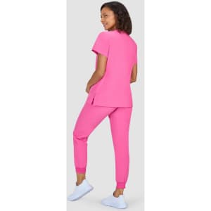 A model wearing a bright pink two-piece outfit, consisting of a top and fitted pants, paired with white footwear.