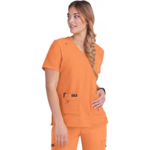 A woman wearing an orange medical scrub top with short sleeves and two front pockets. The top has a branding logo.